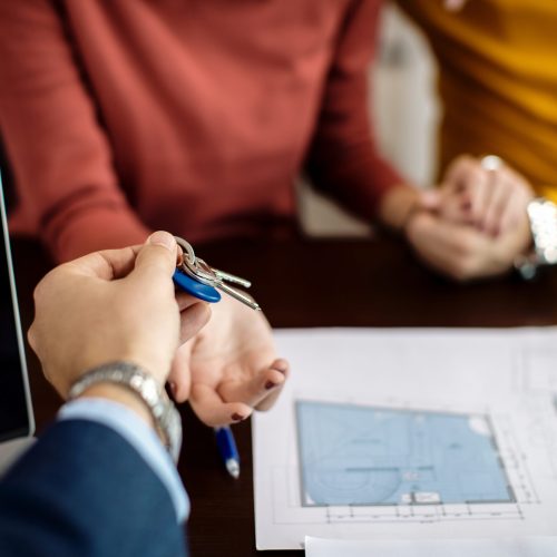 Close-up of a couple receiving keys of their new home on a meeting in the office.