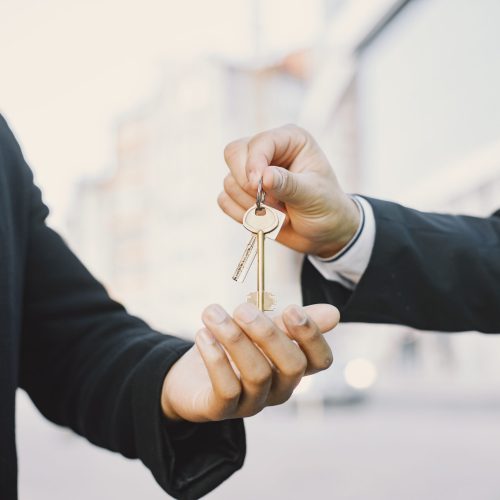 Buying property concept. Man in uniform giving the keys to black man. Close up.