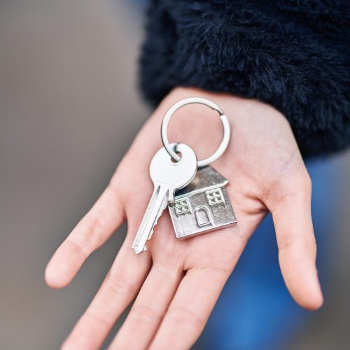 Young woman holding key of new home at street
